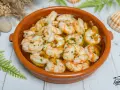 Gambas al ajillo burbujeantes en cazuela de barro, con perejil picado y un toque de aceite de oliva. ¡Un clásico irresistible!