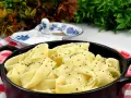 Pappardelle w kremowym sosie alfredo, posypane świeżo mielonym pieprzem, podane w czarnym naczyniu na czerwono-białej kratce.