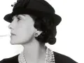 Coco Chanel, con sigaretta e perle, icona di stile, ci ricorda dove è nata Coco Chanel, un'ispirazione senza tempo.