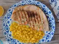 Delicioso emperador a la plancha con patatas fritas crujientes, servido en un plato con diseño azul y blanco. Un toque de limón completa esta apetitosa presentación.