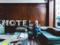 Kobieta z kawą siedzi na kanapie w hotelu. Zastanawia się, ile zarabia technik hotelarstwa.