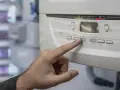 Mano presionando un botón en la caldera de gas, indicando posibles problemas. La pantalla muestra "02".