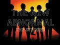 Sylwetki członków zespołu The Strokes na tle pomarańczowego światła. Tytuł albumu "The New Abnormal" i nazwa zespołu widoczne w neonowym stylu.