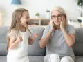 Mała dziewczynka krzyczy, gdy dziecko rządzi rodzicami. Babcia zatyka uszy, wyraźnie zirytowana.
