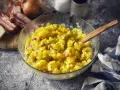 Ein Schüssel voller warmer Kartoffelsalat mit Speck und Zwiebeln, bereit zum Servieren.