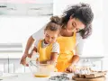 Une mère et sa fille préparent une recette, la petite verse du lait ribot dans un bol.