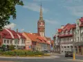 Kętrzyn atrakcje: malowniczy rynek z charakterystyczną wieżą kościelną, kolorowe kamienice i zielone skwery.