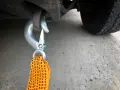 Gancio metallico agganciato al telaio di un'auto, pronto per iniziare a come trainare una macchina. La cinghia arancione è visibile.