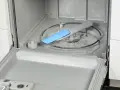 Water and suds fill the bottom of a dishwasher, with a blue spray arm component visible. This image shows a step in how to fix a clogged dishwasher.