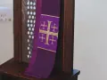 Fioletowa stuła z krzyżami, symbol przygotowania do spowiedzi wielkanocnej, wisi na drewnianej kratce konfesjonału.