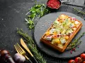Gaufre rectangulaire garnie de dés de fromage, de fruits et de pousses, servie sur une ardoise. Une délicieuse pâte à gaufre salée prête à être dégustée.