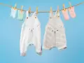 Ropa de bebé colgada para secar: dos peleles con caritas de oso y calcetines a juego. ¡El momento perfecto para saber cuando lavar la ropa del bebé!