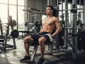 Un homme musclé se repose dans une salle de sport, profitant de son temps de repos idéal musculation.
