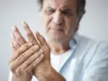 Mann hält seine Hand, da seine Finger schmerzen beim Beugen.