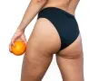 Mujer con naranja en mano, mostrando sus piernas y glúteos con celulitis. ¿Buscas como quitar celulitis piernas?