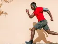 Hombre corre con audífonos y brazalete para celular. ¡Correr quema grasa y te da energía!