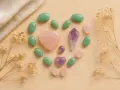 Cristales en forma de corazón y ovalados, incluyendo amatista y cuarzo rosa, dispuestos en un círculo. Una piedra equilibrio emocional.