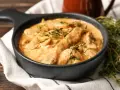 Cremiges Rindfleisch mit Pilzen, garniert mit frischem Thymian. Ein köstliches stroganoff rezept original, serviert in einer schwarzen Schüssel.