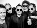Pięciu mężczyzn w okularach przeciwsłonecznych, gotowych na koncert. Jeden z nich pokazuje kciuk w górę, jakby mówił "t.love hau! hau!".