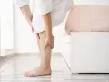 Kobieta w szlafroku masuje łydkę, odczuwając ból. Może to być jeden z objawów miażdżycy.