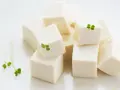 Kostki białego tofu, idealna podstawa do wielu dań, ozdobione świeżymi kiełkami.
