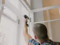 Mężczyzna montuje nowe okno, szukając najlepszej wymiana okien cena.