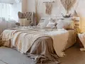 Acogedora decoracion boho habitacion con cama mullida, sillón, macramé y faroles.