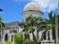 Biała, zabytkowa budowla z kopułą i palmami na tle błękitnego nieba. Klimatyczne zanzibar miasto.