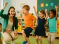 Niños y maestra celebran, mostrando su **capacidad psicomotriz** con alegría en un aula colorida.