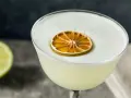 En krämig gin sour med ett skivat torkat limefrukt som dekoration.