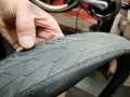 En hand håller ett cykeldäck med små taggar som sticker ut. Däcket ser slitet ut, redo för cykel lagning.