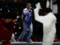 Un rappeur sur scène, micro en main, devant une foule lumineuse. Une performance qui rappelle l'énergie du rap francais.