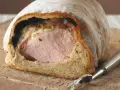 Saftiges Kassler im knusprigen Brotmantel, bereit zum Anschneiden. Ein Festmahl!