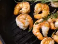 Gambas a la plancha jugosas y doradas, con ramitas de tomillo fresco sobre una sartén de hierro fundido.