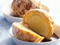 Zwei Portionen gebratenes Eis, umhüllt von Mandelsplittern und mit Puderzucker bestäubt, serviert in weißen Schalen.