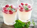 Dwa orzeźwiające drinki z limoncello, malinami i miętą na drewnianym blacie. Idealne na letnie popołudnie.