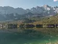 Idyllischer campingplatz in den bergen am see, mit spiegelglatter Wasseroberfläche und bewaldeten Hängen.