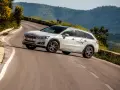 Białe kombi Peugeot 508 RXH na krętej drodze w górach.