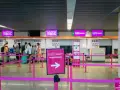 Kasa Wizz Air, gdzie pasażerowie dokonują self check-in. Różowe taśmy wyznaczają kolejkę do stanowisk odprawy.