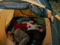 Ein Paar kuschelt eng in einem Zelt. Die **Isomatte unter der Luftmatratze** sorgt für Komfort.