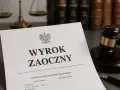 Dokument "Wyrok zaoczny" na biurku prawnika, obok młotka sędziowskiego i wagi sprawiedliwości. Czas na sprzeciw od wyroku zaocznego.