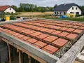 Budowa domu w toku. Widoczny strop gęstożebrowy z pustaków ceramicznych, przygotowany do zalania betonem.