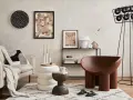 Przytulny salon z kanapą w tkaninie boucle, ozdobiony abstrakcyjnym obrazem i designerskim fotelem.