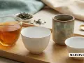 Quatre tasses de thé, dont une en verre remplie d'une infusion ambrée, invitent à choisir quel thé déguster.