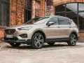 Beiger Seat Tarraco vor Backsteinhaus. Keine Seat Tarraco Probleme hier, nur stilvolles Fahren.