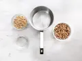 Vorbereitung zum Bohne kochen: zwei Schüsseln mit Schwarzaugenbohnen, ein Topf und eine Schüssel Wasser auf Marmoruntergrund.