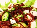Salade fraîche avec des cubes de tofu, des rondelles de concombre, des oignons verts et une généreuse portion d'algue rouge séchée.