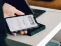 Dłoń trzyma smartfon z aplikacją Blik i kodem transakcji nad terminalem płatniczym.