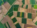 Widok z lotu ptaka na mozaikę pól uprawnych, gdzie zielone i brązowe pasy tworzą malownicze **klasy gruntów rolnych**.