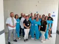 Grupa lekarzy i pielęgniarek w uniformach medycznych pozuje do zdjęcia w szpitalnym korytarzu.